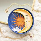 Bandeja circular azul con sol naranja y fases lunares junto a una bandeja amarilla en forma de luna creciente con rostro.