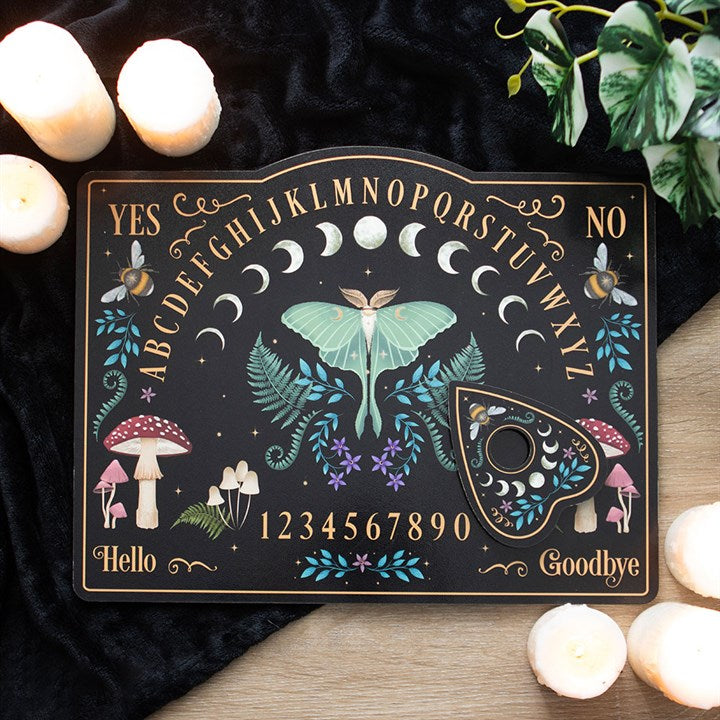 Tablero Ouija de madera o material rígido con diseño de bosque oscuro, letras del abecedario y planchette decorada.